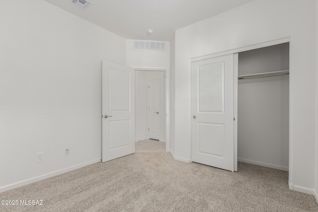 unfurnished bedroom with light carpet and a closet