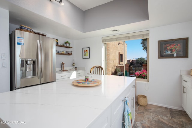 kitchen featuring light stone countertops, white cabinetry, and stainless steel fridge with ice dispenser