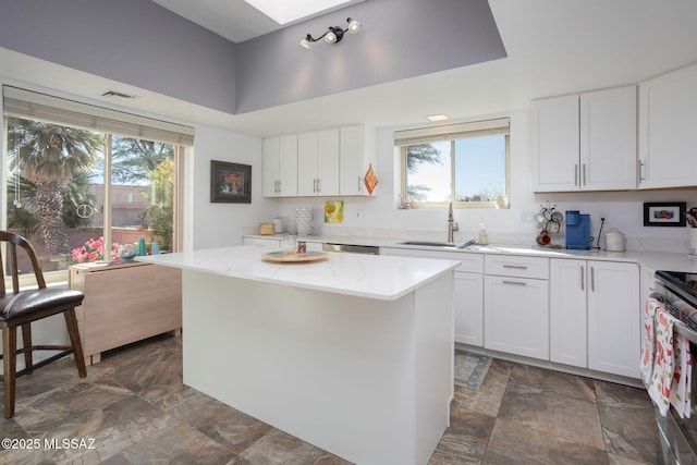 kitchen featuring light stone countertops, white cabinetry, a center island, and stainless steel appliances