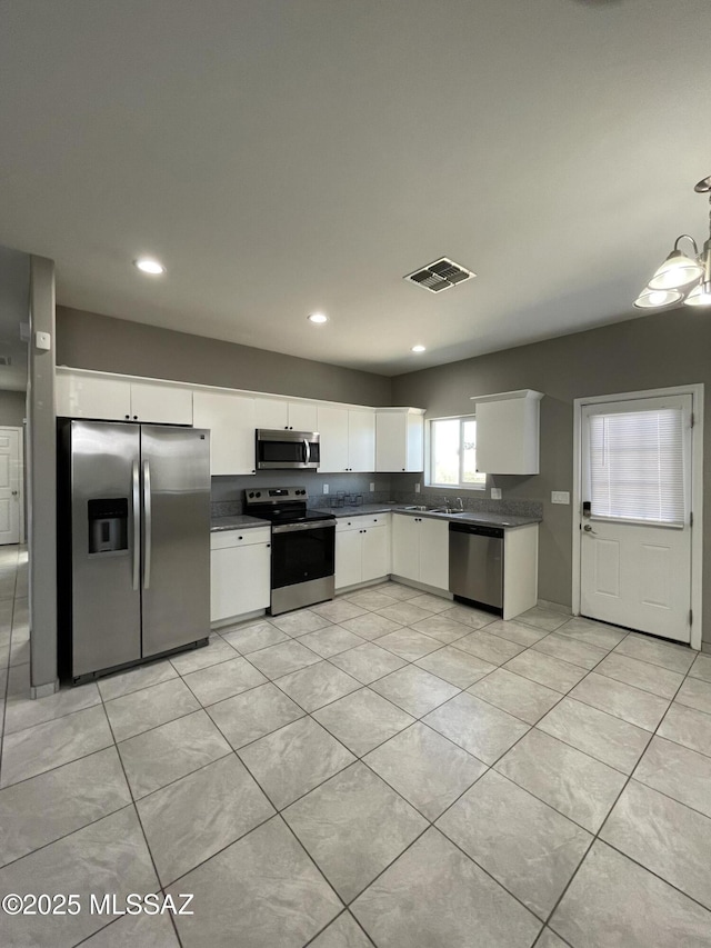 kitchen featuring light tile patterned floors, stainless steel appliances, pendant lighting, and white cabinets