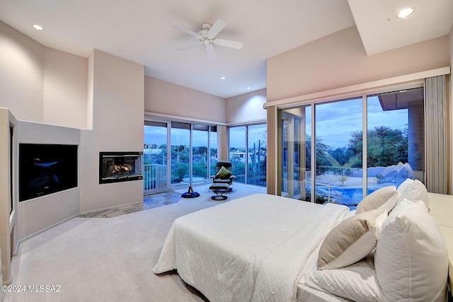 carpeted bedroom with ceiling fan, access to exterior, and a multi sided fireplace