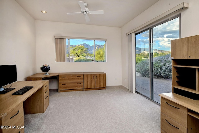 office space featuring a mountain view, light colored carpet, and ceiling fan