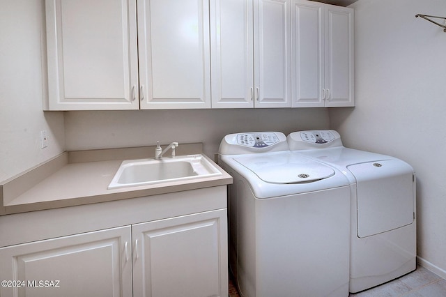 washroom with cabinets, washer and dryer, and sink