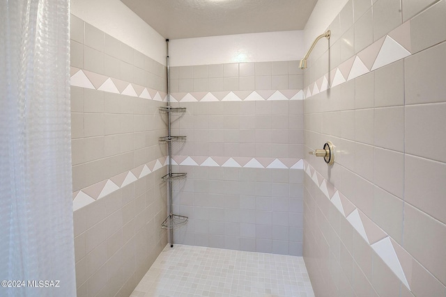 bathroom featuring a textured ceiling and a tile shower