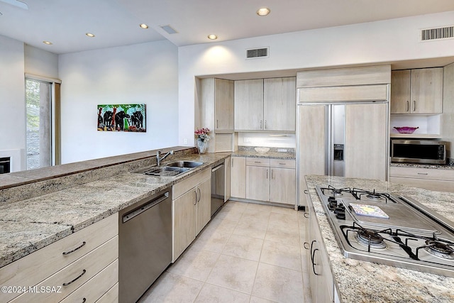 kitchen with dishwashing machine, gas stovetop, dishwasher, light stone counters, and sink