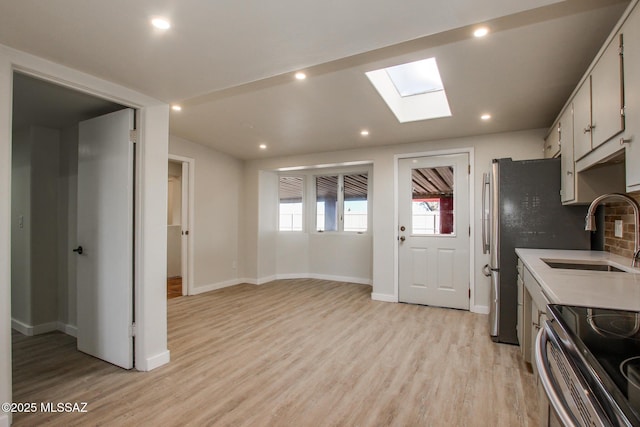 kitchen featuring a skylight, recessed lighting, a sink, light countertops, and light wood-type flooring