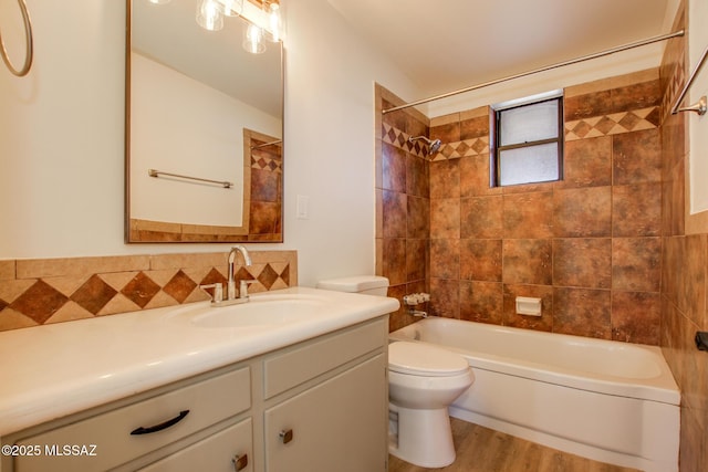 full bathroom with toilet, tiled shower / bath, wood-type flooring, and vanity