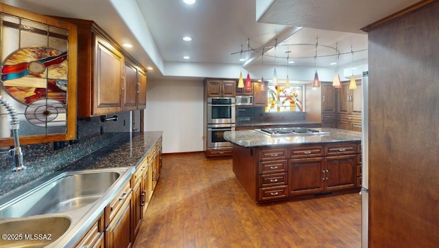 kitchen featuring pendant lighting, dark hardwood / wood-style flooring, stainless steel appliances, dark stone countertops, and decorative backsplash