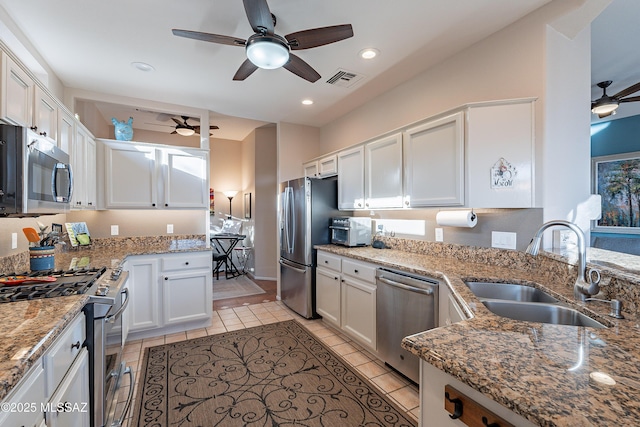 kitchen with light tile patterned flooring, sink, appliances with stainless steel finishes, light stone countertops, and white cabinets