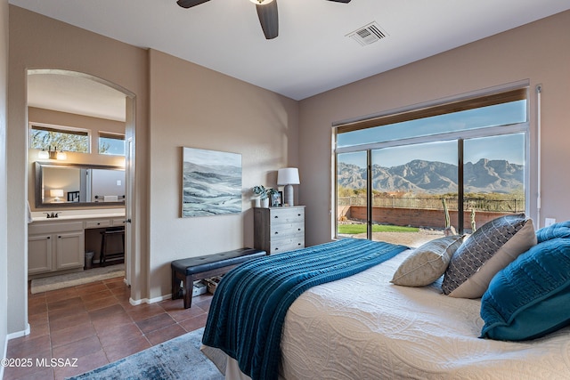 tiled bedroom featuring sink, ensuite bath, ceiling fan, a mountain view, and access to outside