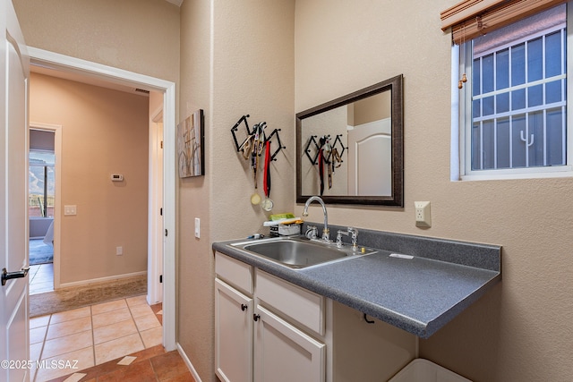 kitchen featuring sink, light tile patterned floors, and white cabinets