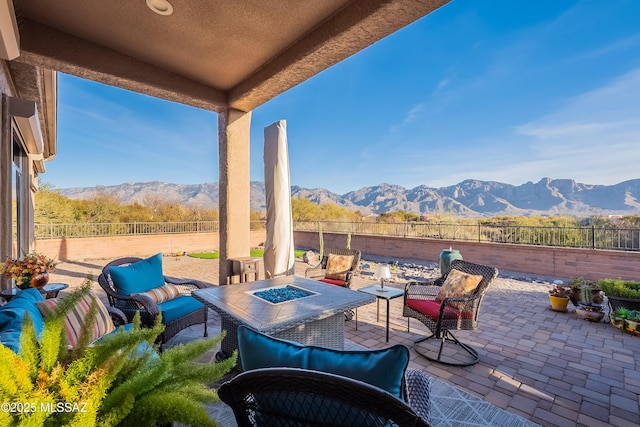 view of patio with a mountain view and an outdoor living space with a fire pit