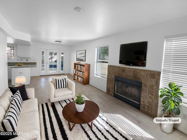 living room featuring light hardwood / wood-style flooring, a tile fireplace, and a healthy amount of sunlight