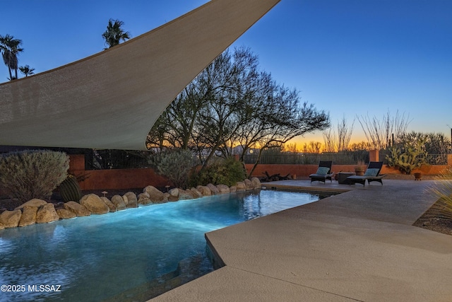 pool at dusk featuring a patio area