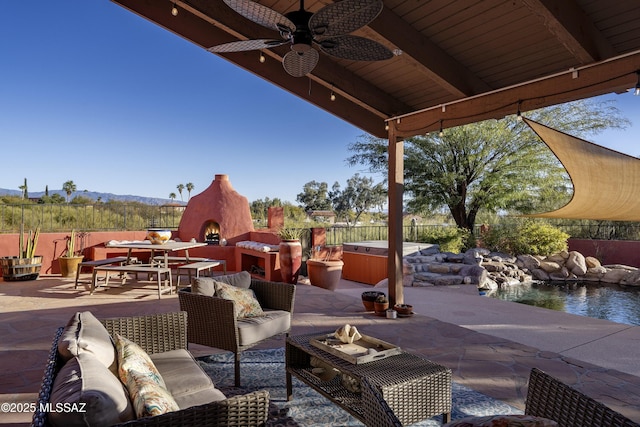 view of patio with a water view, an outdoor living space with a fireplace, and ceiling fan