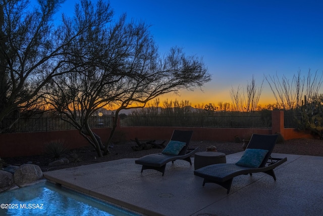 pool at dusk with a patio area