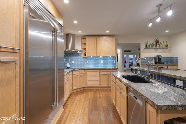 kitchen with wall chimney exhaust hood, sink, light brown cabinets, appliances with stainless steel finishes, and a kitchen island