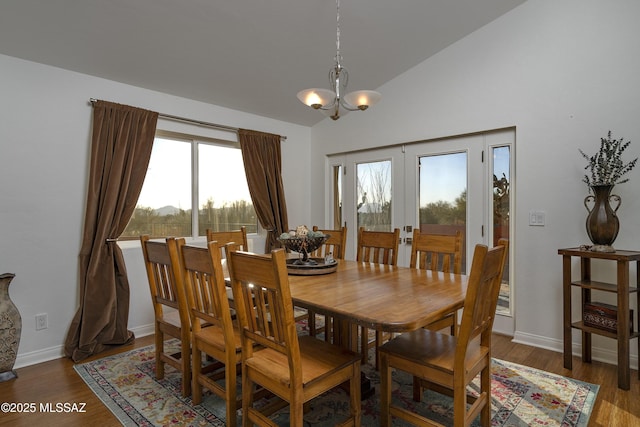 dining area featuring lofted ceiling, dark wood-type flooring, an inviting chandelier, and french doors