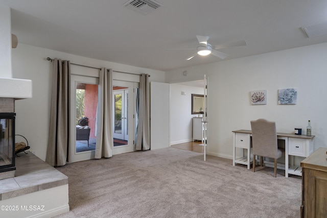 office area featuring a multi sided fireplace, light colored carpet, and ceiling fan