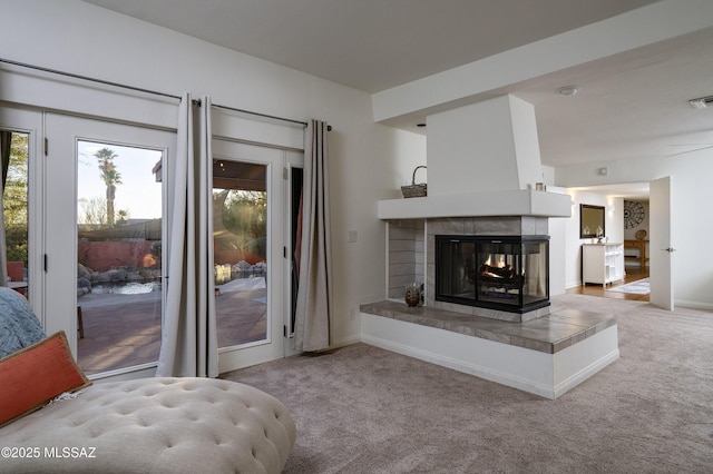 carpeted bedroom with access to exterior and a tile fireplace