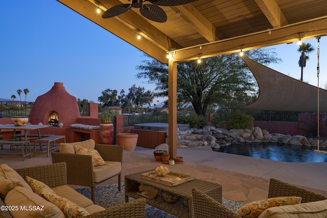 patio terrace at dusk featuring ceiling fan and an outdoor living space with a fireplace