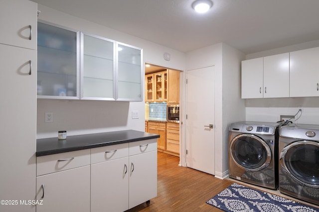 laundry area with cabinets, washing machine and clothes dryer, and light wood-type flooring