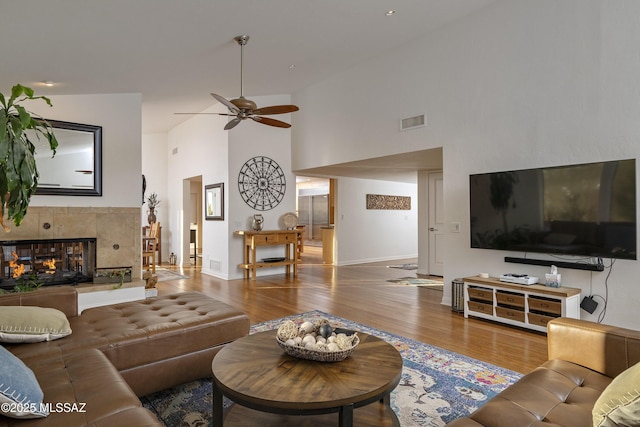 living room with hardwood / wood-style flooring, a multi sided fireplace, ceiling fan, and high vaulted ceiling