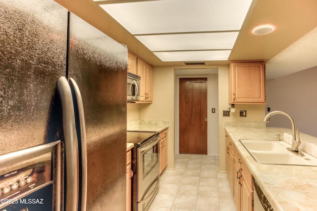 kitchen with light tile patterned floors, appliances with stainless steel finishes, sink, and light brown cabinets