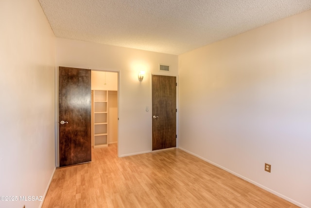 spare room featuring a textured ceiling and light wood-type flooring