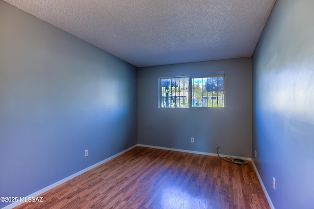 spare room with dark wood-type flooring and a textured ceiling