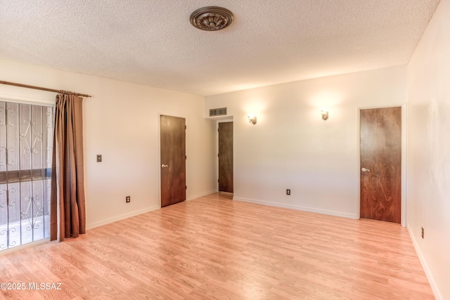 empty room featuring a textured ceiling and light hardwood / wood-style flooring