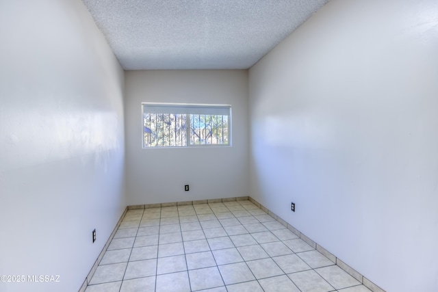 spare room with a textured ceiling and light tile patterned flooring