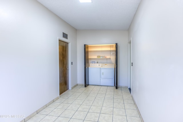 hall with a textured ceiling and washing machine and clothes dryer