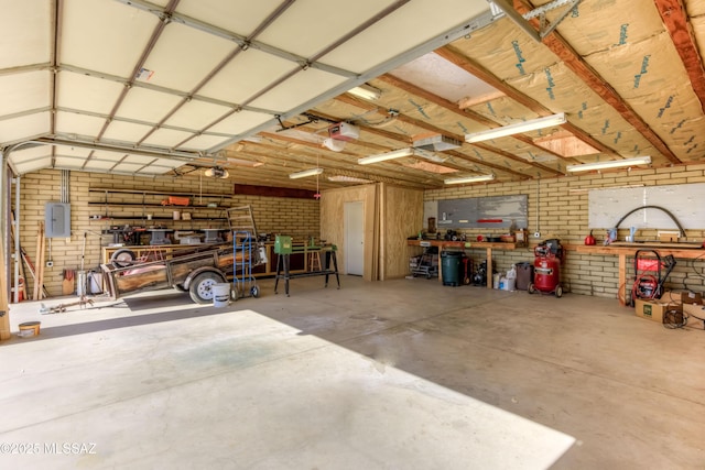 garage with a workshop area, a garage door opener, and electric panel