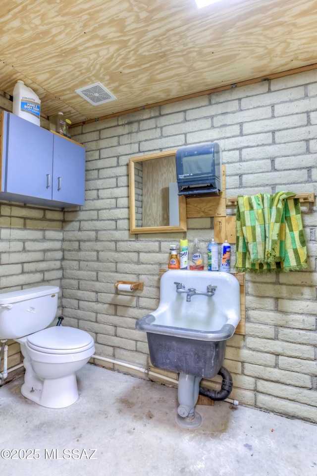 bathroom featuring toilet, wood ceiling, and concrete flooring