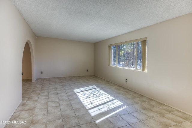 unfurnished room with a textured ceiling and light tile patterned floors