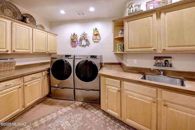 laundry room featuring cabinets, independent washer and dryer, and sink