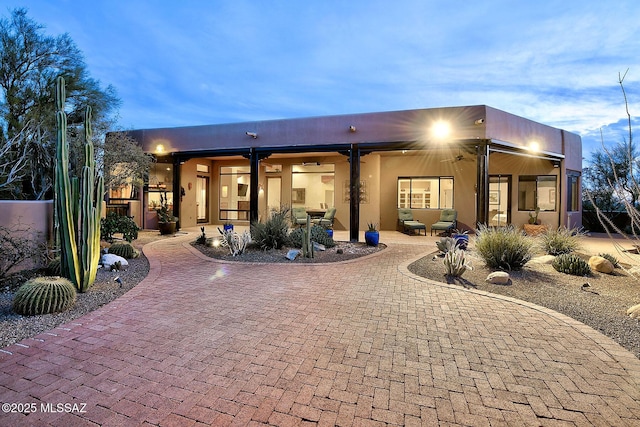 back house at dusk featuring a patio