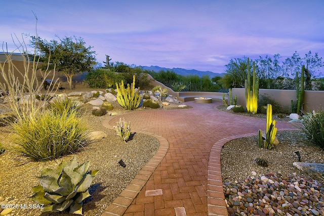 yard at dusk featuring a mountain view and a patio area