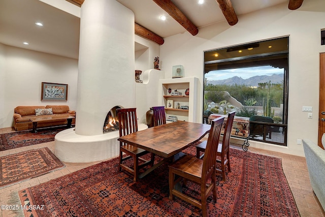 dining area featuring beamed ceiling, a large fireplace, and a mountain view