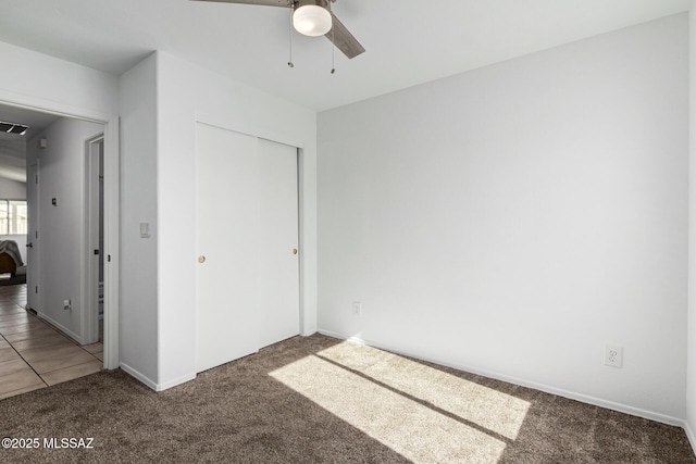 unfurnished bedroom with carpet floors, ceiling fan, and a closet