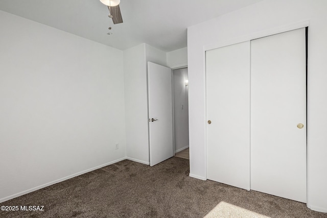 unfurnished bedroom featuring ceiling fan, dark carpet, and a closet