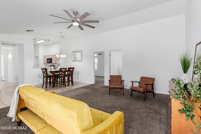 tiled living room with ceiling fan with notable chandelier and lofted ceiling