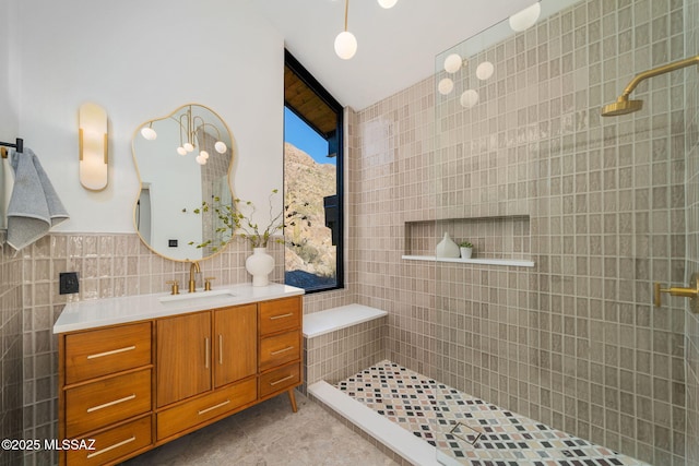 bathroom with tile walls, vanity, tile patterned floors, and a tile shower