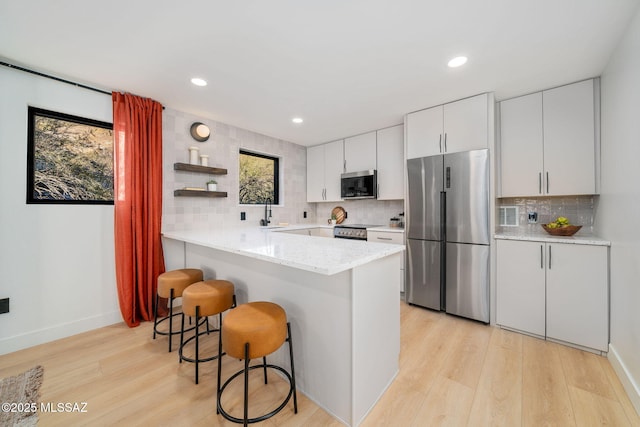 kitchen with white cabinetry, appliances with stainless steel finishes, a healthy amount of sunlight, and a kitchen breakfast bar