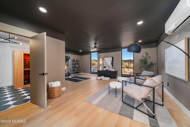 cinema room featuring ceiling fan, an AC wall unit, and light wood-type flooring