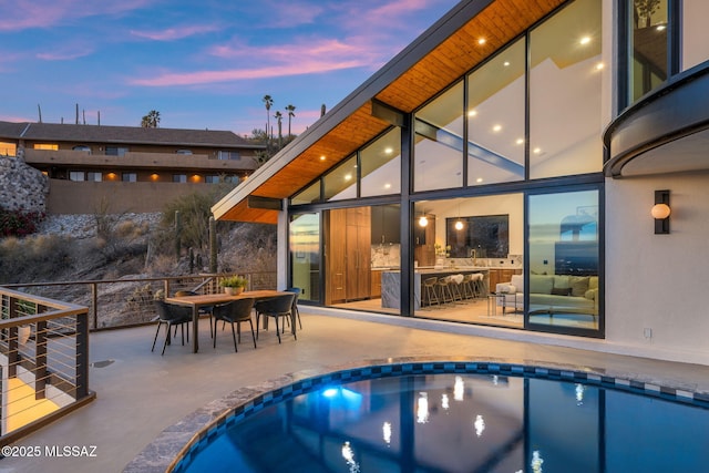 pool at dusk featuring a patio