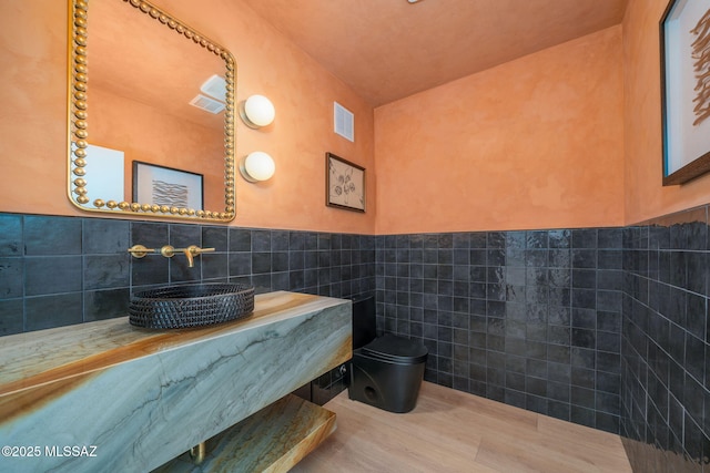 bathroom featuring tile walls and toilet