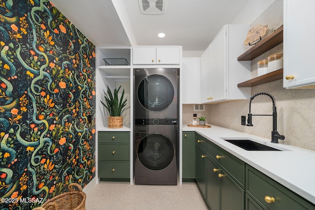 washroom with stacked washer and dryer, sink, and cabinets