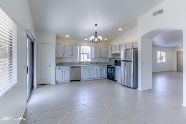 kitchen with plenty of natural light, vaulted ceiling, hanging light fixtures, and appliances with stainless steel finishes